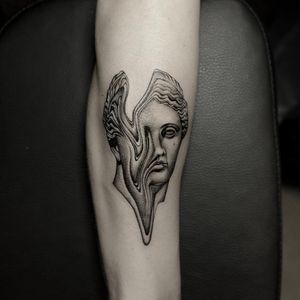 A stunning blackwork and illustrative tattoo of a statue woman on the arm, expertly done by Oek.