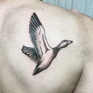This stunning blackwork tattoo of a duck bird on the upper back is expertly done by Farhaad Khan.