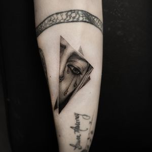 Blackwork tears and woman design on forearm by Oek, combining realism and illustration style.