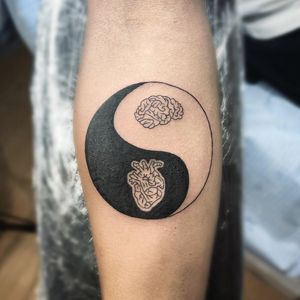 Intricate blackwork tattoo on forearm by Farhaad Khan, featuring a heart, brain, and yin & yang symbol in fine-line illustrative style.