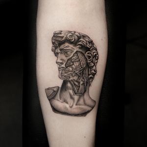 Get inked with Oek's illustrative blackwork tattoo of a muscular man on your upper arm for a bold and unique look.