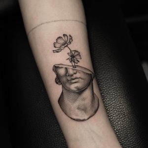 Get a unique tattoo on your forearm by Oek, featuring a combination of dotwork and fine line styles with a beautiful flower and statue motif.