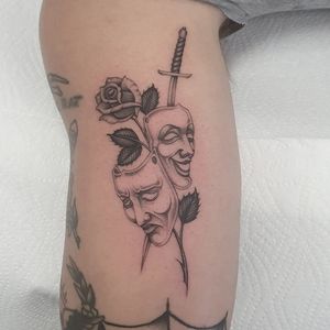 Unique blackwork tattoo on upper arm combining a flower, sword, and mask, expertly designed by Dani Mawby.
