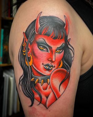Get a bold new school tattoo of a devil woman on your upper arm in London for a fierce and edgy look.
