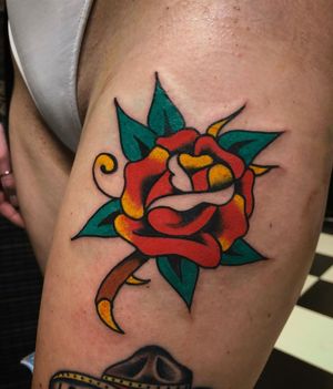 Get a beautiful traditional rose tattoo on your thigh in London, GB. Perfect mix of bold colors and classic design