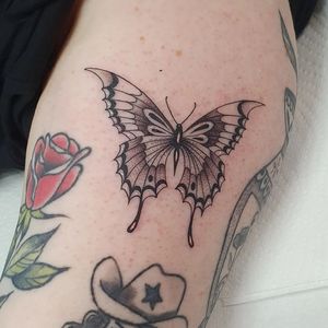 Blackwork butterfly tattoo on the upper arm, designed by Dani Mawby in an illustrative style.