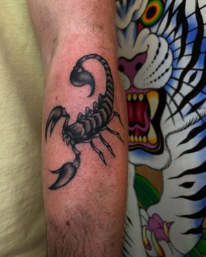 Get a striking black and gray traditional scorpion tattoo on your arm in London, GB. Let this powerful design symbolize your strength and determination.