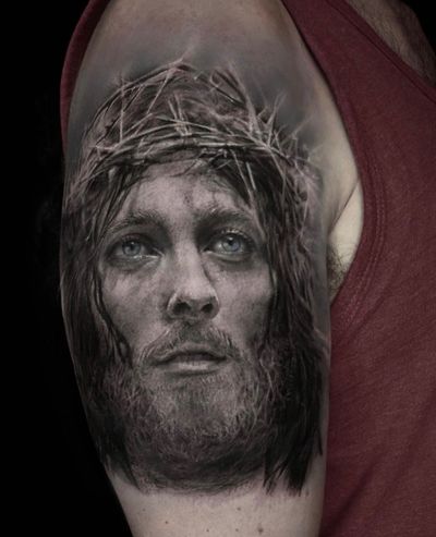 Experience divine artistry with Mengni Yang's realistic black and gray Jesus tattoo on your upper arm.