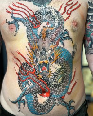 Get a stunning Japanese dragon chest tattoo by Stewart Robson for a bold and fierce look. Bring ancient mythology to life on your skin!