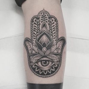 Get mesmerized by Dani Mawby's intricate blackwork design featuring a mandala, lotus flower, hamsa, and eye on your lower leg.