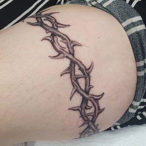 A stunning blackwork and illustrative tattoo of intricate thorns on the upper leg by tattoo artist Dani Mawby.