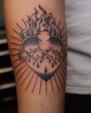 Illustrative forearm tattoo by artist Carlos Hernandez, featuring a bold heart surrounded by intricate thorns.