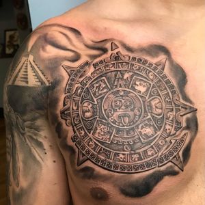 Black and gray realistic tribal tattoo featuring a mesmerizing mandala design and intricate mask, by talented artist Carlos Hernandez.