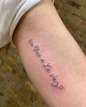 Get a stylish fine line tattoo with your favorite quote on your upper arm by the talented artist Carlos Hernandez.