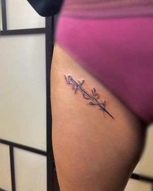Beautiful fine line illustrative tattoo of a flower and sword on the upper leg by talented artist Carlos Hernandez.