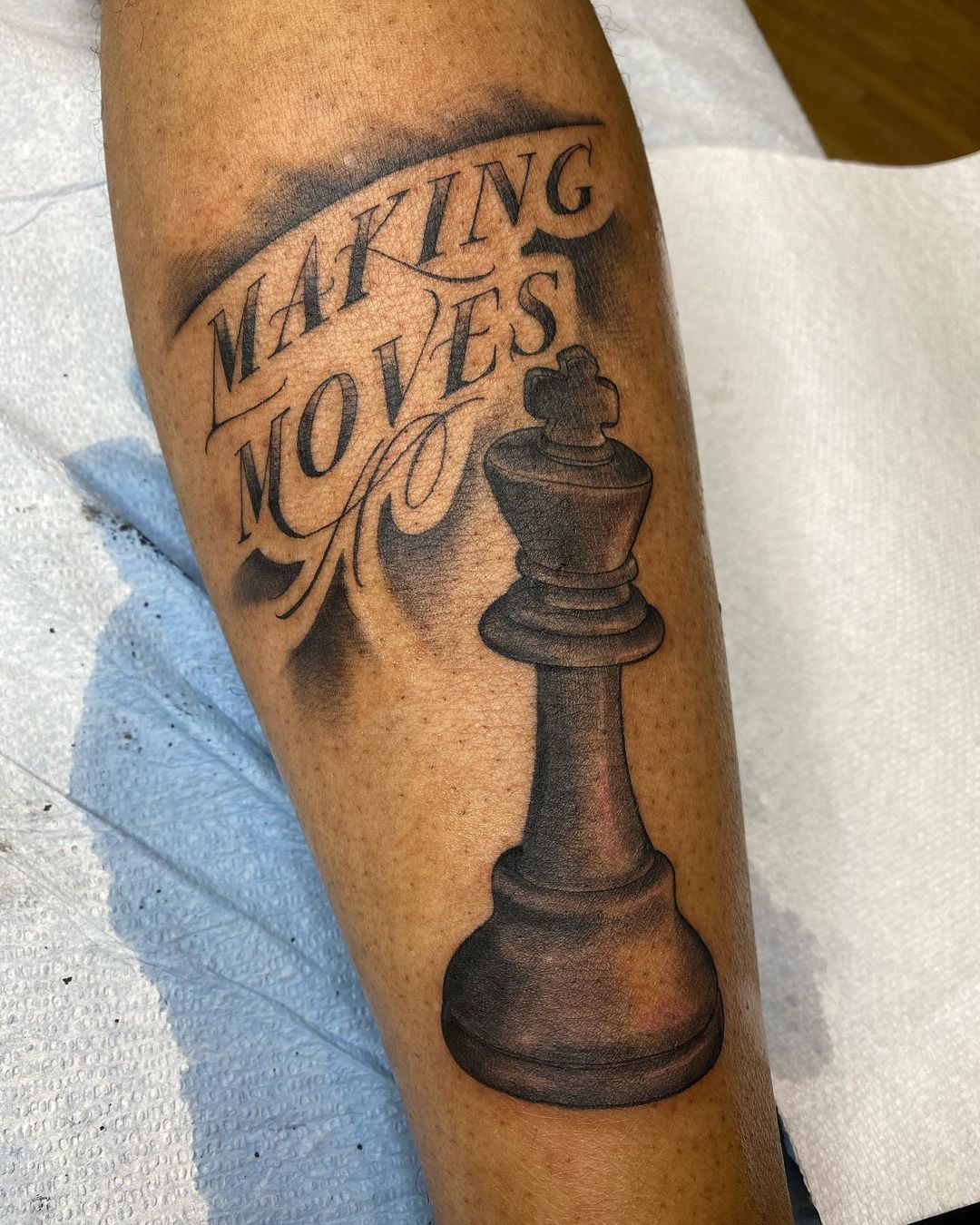 Micro-realistic chess king tattoo on the inner forearm.