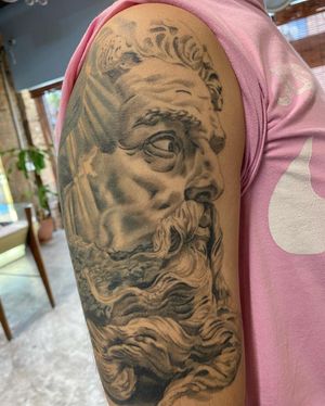Transform your upper arm with a detailed black and gray Poseidon design by the talented artist Carlos Hernandez.