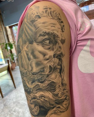 Transform your upper arm with a detailed black and gray Poseidon design by the talented artist Carlos Hernandez.