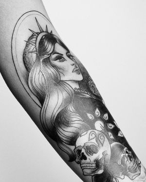 A striking blackwork forearm tattoo featuring a powerful mix of a flower, skull, woman, and crown. Designed by Marcos.