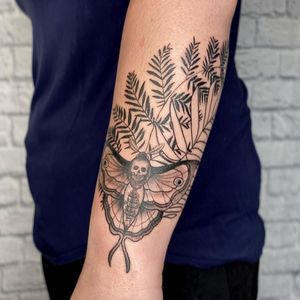 Unique blackwork design by Marcos showcasing a moth and leaf illustration on the forearm.