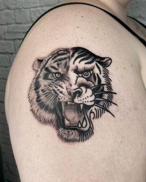 Get a fierce and detailed blackwork tiger tattoo on your upper arm by the talented artist Marcos. Stand out with this stunning design!