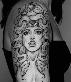 Unique blackwork tattoo featuring a snake and woman design, expertly done by Marcos on the upper arm.