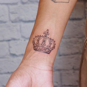 Elegant and detailed crown design on the forearm by the talented artist Marcos. Perfect for a touch of royalty in your style.