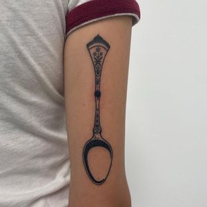 Unique blackwork tattoo featuring an illustrative spoon pattern on the upper arm by Nic V.