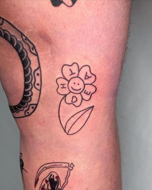 Unique and striking tattoo featuring a blackwork flower, lettering, and illustrative design on the upper leg. Created by the talented artist Sasha.