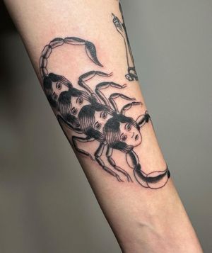 This blackwork and illustrative tattoo features a fierce scorpion crawling on a woman's forearm. Designed by Sasha.