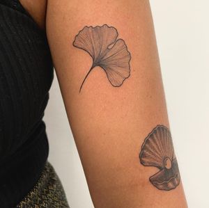 Illustrative tattoo by Nic V featuring a stunning combination of a flower and shell design on the upper arm.