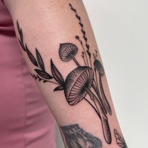 Unique blackwork tattoo by Nic V featuring a beautiful combination of a flower and mushroom design on the arm.