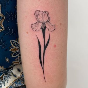 Elegant blackwork design by Nic V, showcasing a beautiful flower motif on the upper arm. Perfect for those seeking a bold and stylish tattoo.