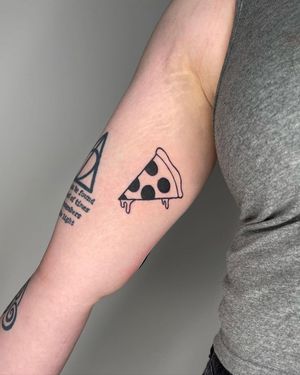 Express your love for pizza with this illustrative blackwork tattoo on your upper arm by Sasha.