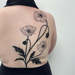 A stunning blackwork flower tattoo on the back, expertly done by the talented artist Nic V. This illustrative design is sure to make a bold statement.