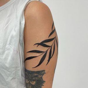 Blackwork upper arm tattoo featuring a detailed leaf design by talented artist, Nic V