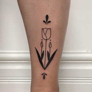 Elegantly detailed flower tattoo by Nic V, showcasing intricate blackwork design on lower leg.