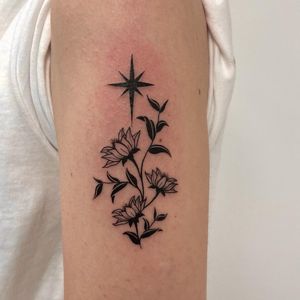 Beautiful blackwork and illustrative tattoo featuring a star and flower motif, created by the talented Nic V.