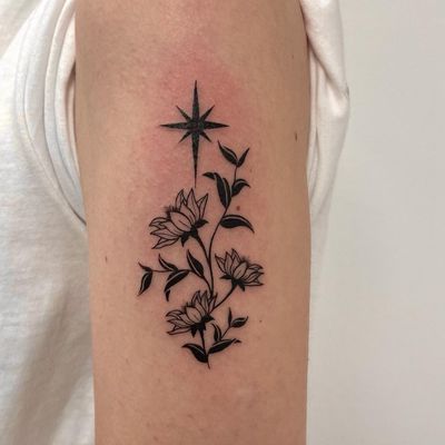 Beautiful blackwork and illustrative tattoo featuring a star and flower motif, created by the talented Nic V.