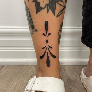 Illustrative tattoo by Nic V featuring a unique pattern design on the lower leg