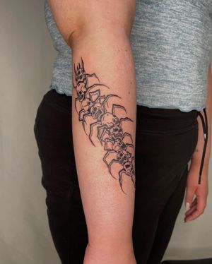 Bold blackwork forearm tattoo featuring a skull and centipede, artistically done by Sasha.