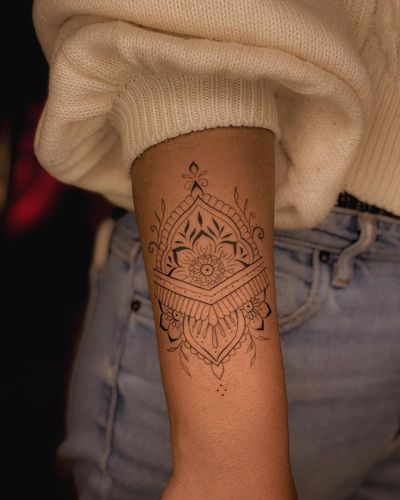 Fabian Lopez Barreda's stunning blackwork tattoo features a detailed mandala flower design on the forearm, blending ornamental and illustrative styles.