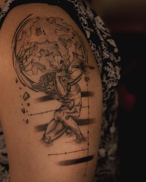 Illustrative black and gray tattoo featuring a man holding the world as an atlas on the upper arm. By Fabian Lopez Barreda.