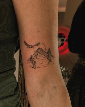 Fine line blackwork tattoo on forearm featuring moon, mountain, bird, and cactus by Fabian Lopez Barreda.