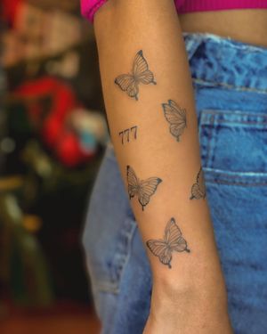 Fine line butterfly tattoo on forearm by artist Fabian Lopez Barreda. Striking blackwork design.