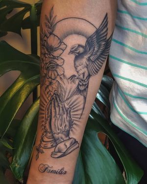 Fabian Lopez Barreda's blackwork forearm tattoo featuring intricate illustrations of a bird, flower, and praying hands.