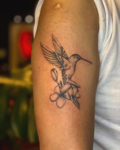 Beautiful blackwork tattoo of a hummingbird and flower on upper arm, done by artist Fabian Lopez Barreda.