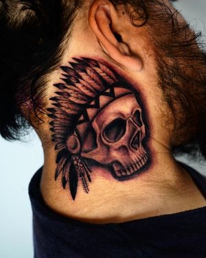 Illustrative black and gray tattoo by Miss Vampira, featuring a skull and feather motif on the neck.