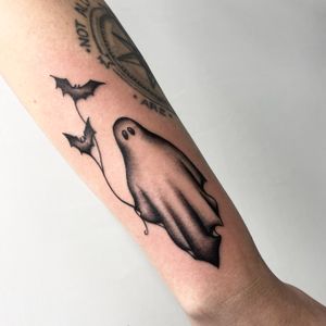 Illustrative tattoo by Miss Vampira featuring a spooky bat and ghost design on the forearm.