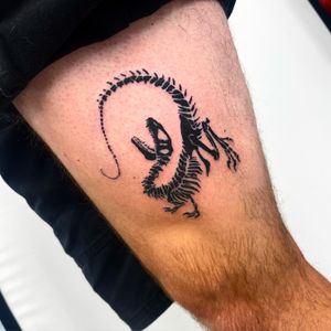 Get inked with a unique blackwork and illustrative tattoo featuring a dino skeleton on your upper leg by the talented artist Miss Vampira.